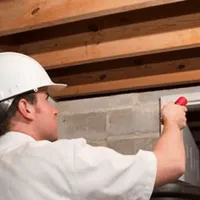 Termite inspection technician checking a basement wall and framing for termite activity in Orange, CA